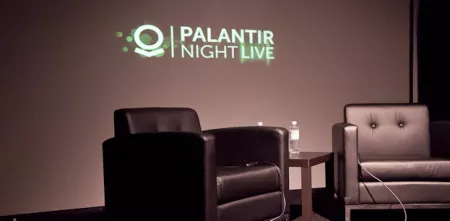 Ein Podium mit zwei schwarzen Sesseln. Im Hintergrund ein Logo "Plantir Night Life".