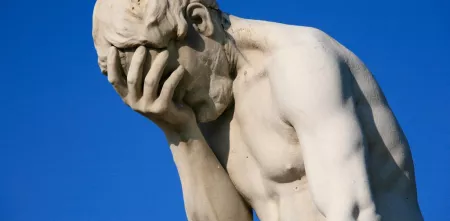Eine Statue, die sich eine Hand vor das Gesicht hält.