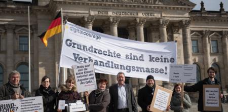 Protestteilnehmer.innen vor dem Reichstagsgebäude. Sie halten ein Transparent mit folgendem Text: „Grundrechte sind keine Verhandlungsmasse.“