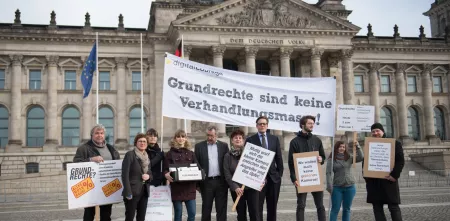 Protestteilnehmer.innen vor dem Reichstagsgebäude. Sie halten ein Transparent mit folgendem Text: „Grundrechte sind keine Verhandlungsmasse.“