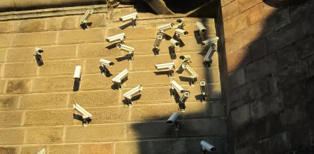 Viele Überwachungskameras an einer Wand, die in jegliche Richtungen gerichtet sind.