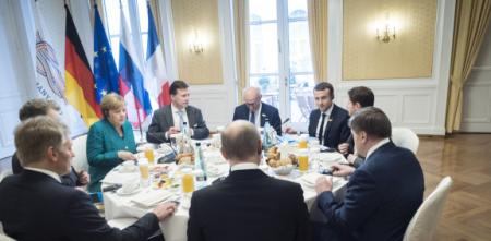 Mehrere Staatschef.innen an einem runden Tisch (u. a. Angela Merkel und Emmanuel Macron).