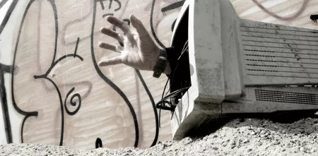 Eine Hand kommt aus einem alten Monitor.