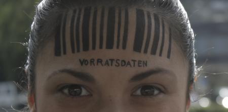 Detailaufnahme vom Kopf einer Person. Auf der Stirn ein Barcode. Darunter steht „Vorratsdatenspeicherung“.