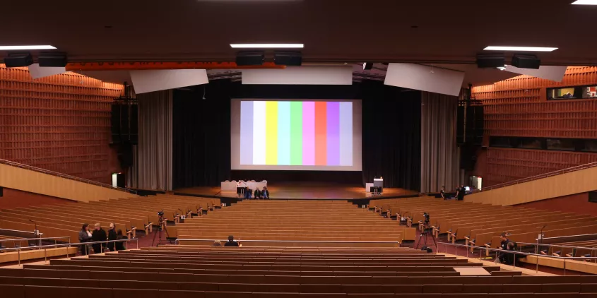 Ein großer Veranstaltungssaal. Auf der Leinwand ein Testbild.