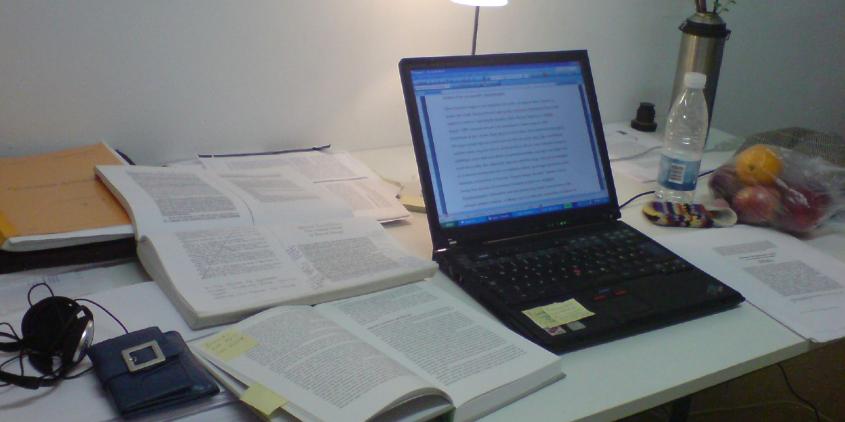 Ein voller Arbeitsplatz mit Laptop und Unterlagen.