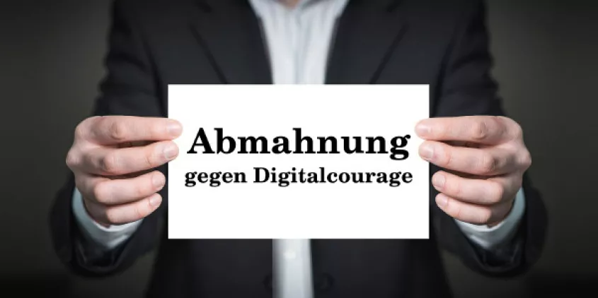 Person mit Anzug hält Schild: Abmahnung für Digitalcourage.