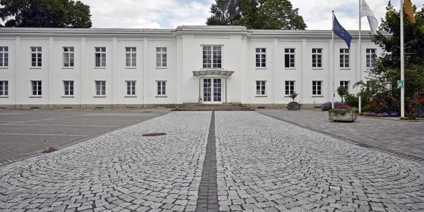 Das Bundeskartellamt von außen (weißes, zweistöckiges Gebäude).