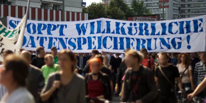 Demonstrant.innen mit einem riesigen Banner „Stoppt willkürliche Datenspeicherung“.