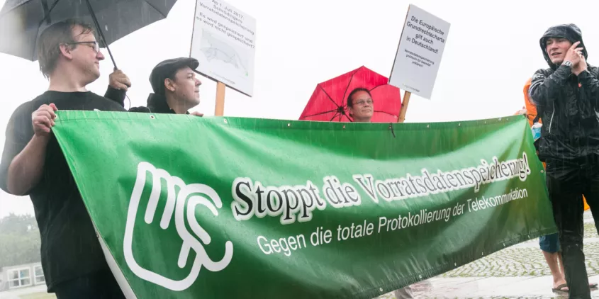 Mehrere Personen halten bei einem Protest ein Banner des AK Vorrat hoch. Darauf steht "Stoppt die Vorratsdatenspeicherung! - Gegen die totale Protokollierung der Telekommunikation."