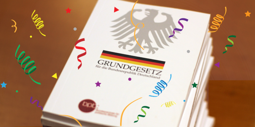 Ein stapel Grundgesetze mit Konfettigrafiken
