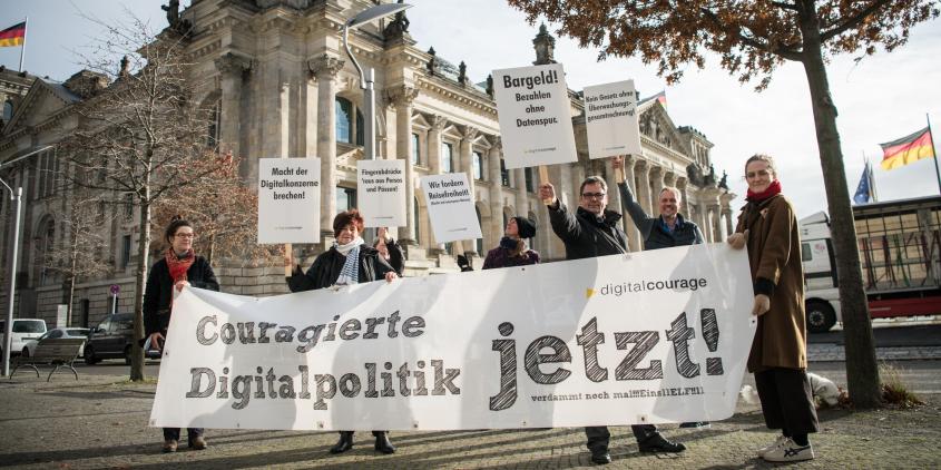 Menschen mit einem Banner „Couragierte Digitalpolitik jetzt!“ vor dem Deutschen Bundestag.