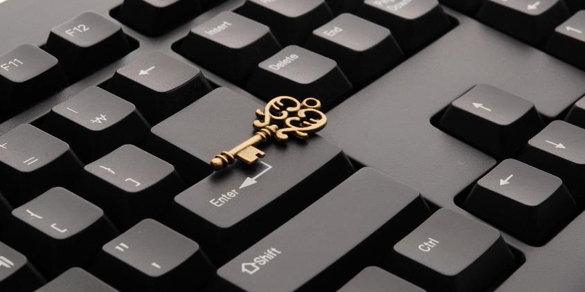 Ausschnitt einer schwarzen Tastatur. Darauf liegend ein goldener Schlüssel.
