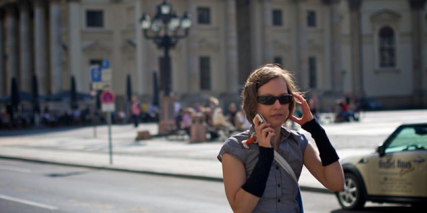 Eine Person mit Sonnenbrille, die am telefonieren ist.