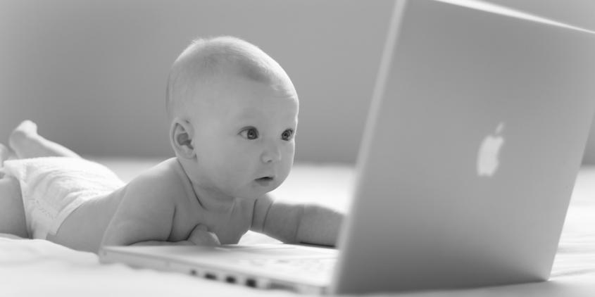 Ein Baby, das auf einen Laptop-Bildschirm starrt (schwarz-weiß).