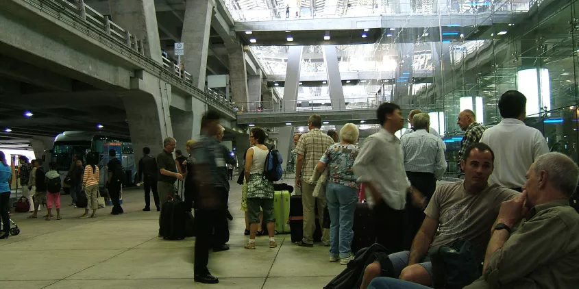 Viele Personenwarten vor einem Flughafenterminal.