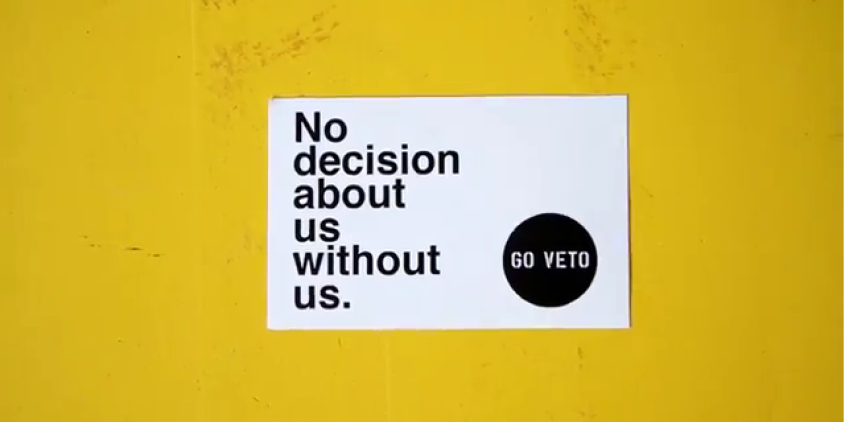 Postkarte auf gelbem Grund: "No decision about us without us. Go veto."