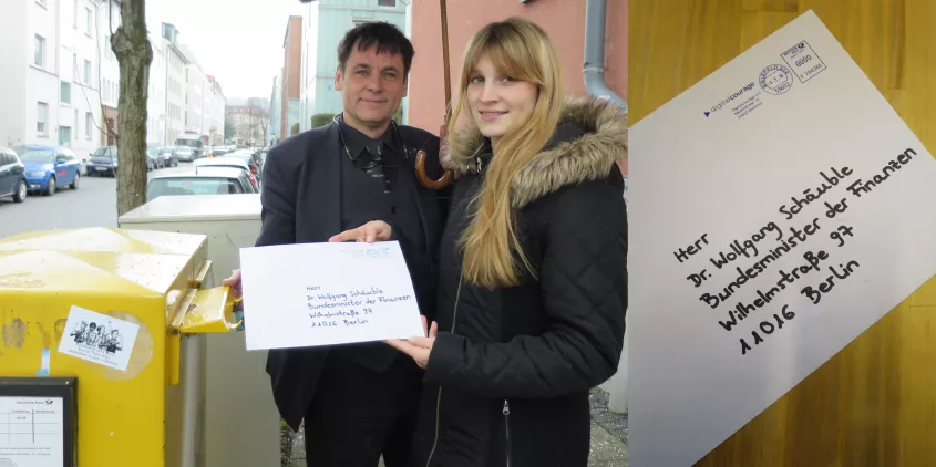 Zwei Teammitglieder von Digitalcourage werfen einen an Wolfgang Schäuble adressierten Brief in einen Briefkasten.
