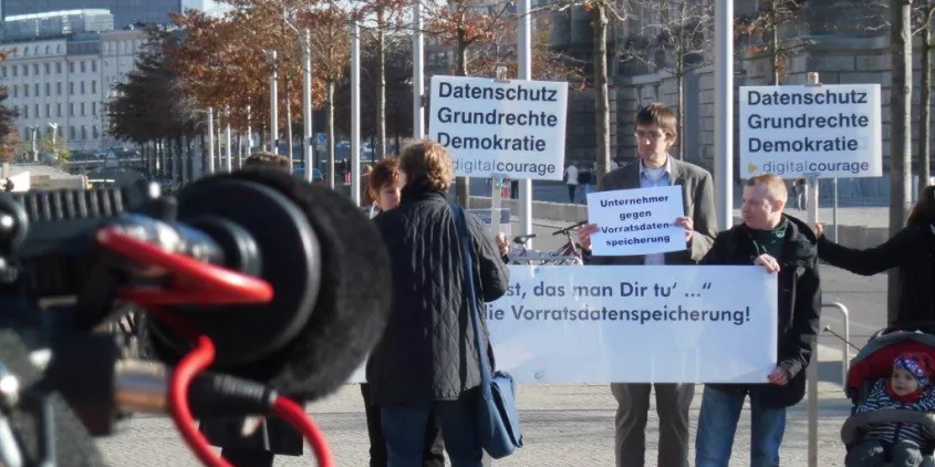 Aktivist.innen mit diversen Bannern und Plakaten (z. B. Datenschutz, Grundrechte, Demokratie).