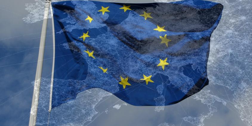 Montage: Eine halbtransparente Europakarte über einer EU-Flagge.