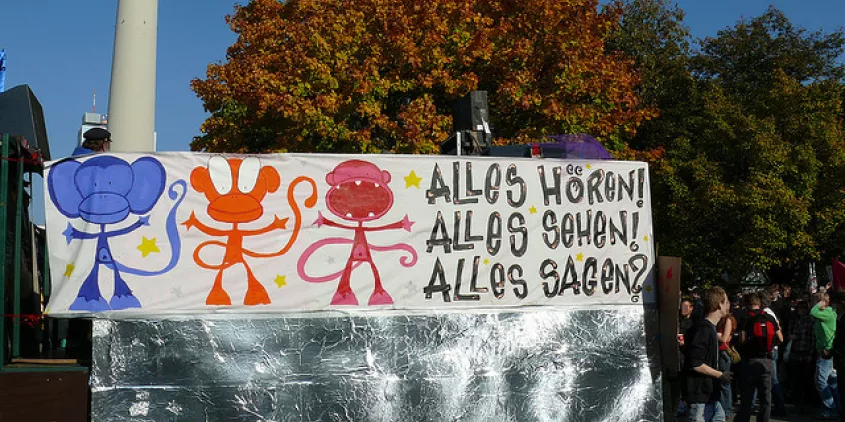 Ein Banner mit 3 Affen. Daneben der Text: „Alles hören! Alles sehen! Alles sagen?“