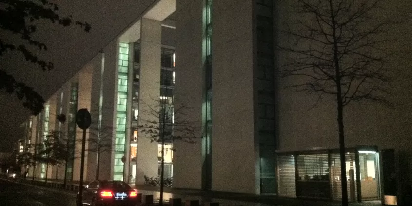 Ein großes Gebäude, teils beleuchtet, bei Nacht.
