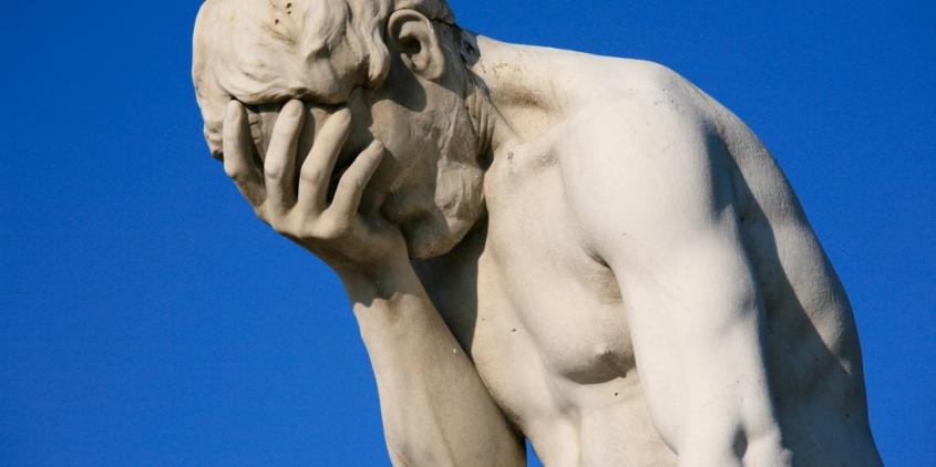 Eine Statue, die sich eine Hand vor das Gesicht hält.