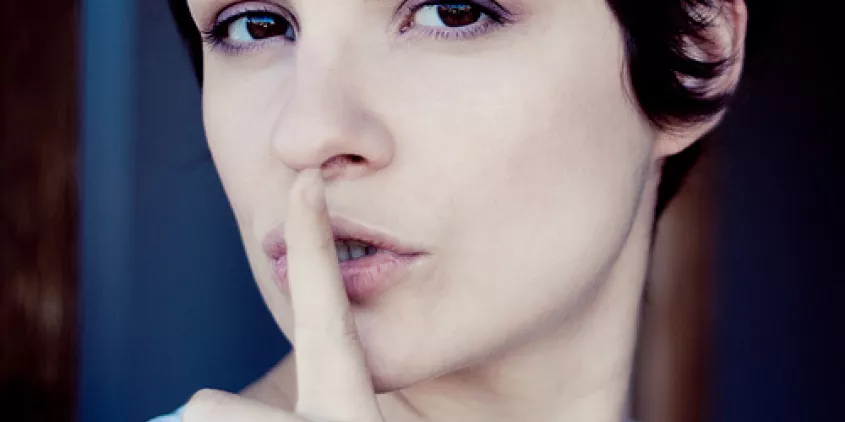 Eine Person, die ihren Zeigefinger vor den Mund hält.