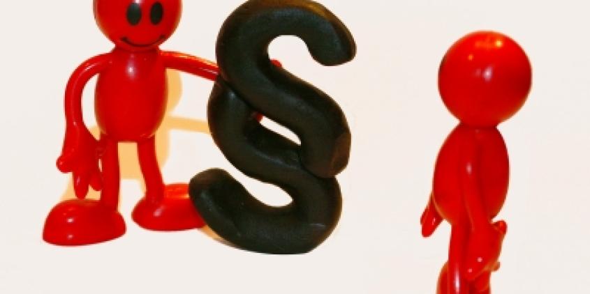 Zwei rote Plastikfigürchen. Eins hält das Paragraph-Symbol.