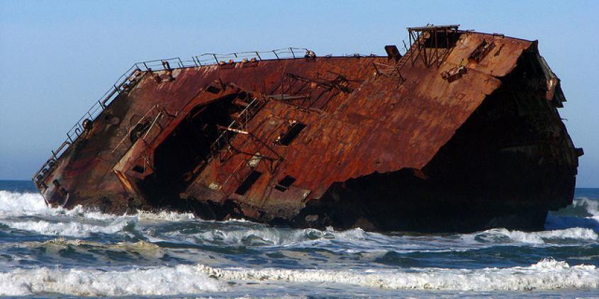 Das Wrack eines Schiffes liegt auf der Seite in Ufernähe.