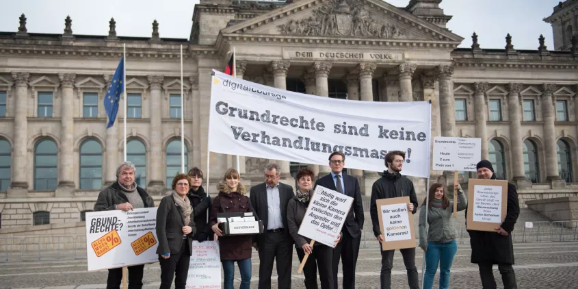 Protestteilnehmer.innen vor dem Reichstagsgebäude. Sie halten ein Transparent mit folgendem Text: „Grundrechte sind keine Verhandlungsmasse.“