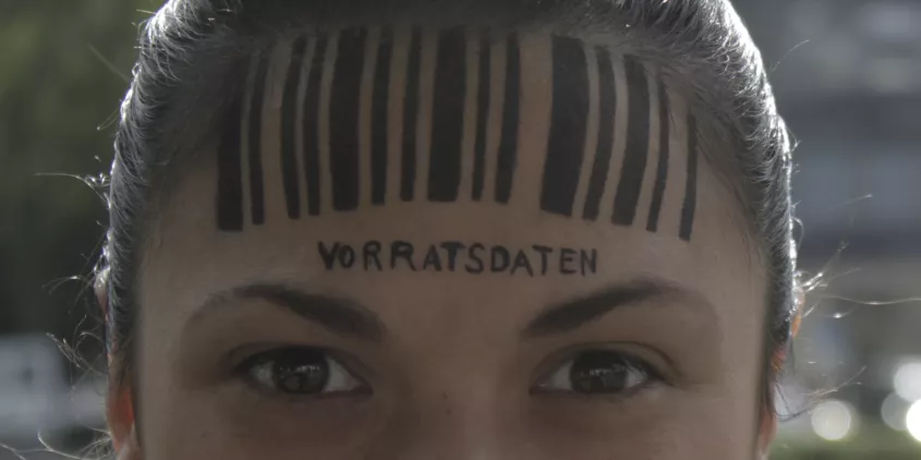 Detailaufnahme vom Kopf einer Person. Auf der Stirn ein Barcode. Darunter steht „Vorratsdatenspeicherung“.
