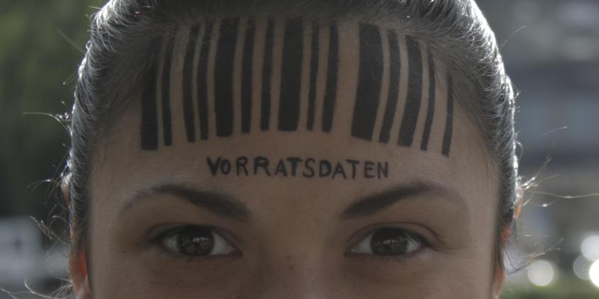 Detailaufnahme vom Kopf einer Person. Auf der Stirn ein Barcode. Darunter steht „Vorratsdatenspeicherung“.
