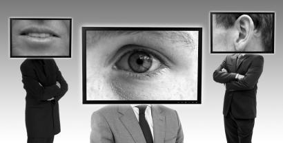 Schwarz-weiß Bild: 3 Personen in Anzug, die anstelle des Kopfes jeweils einen Bildrahmen haben. Darin in Detailaufnahme zu sehen je ein Mund, ein Auge und ein Ohr.