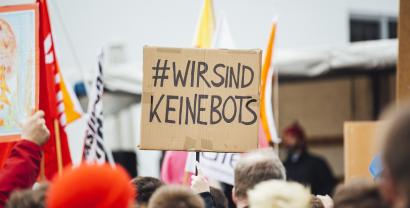 Ein Demoschild mit der Aufschrift: „Wir sind keine Bots“.