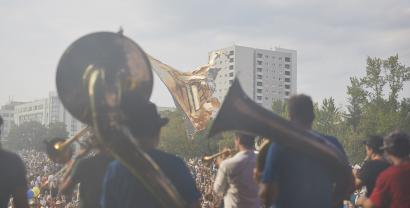 Ein Blasorchester von von hhinten fotografiert, im Hintergrund eine Menschenmenge.