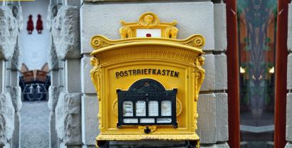 Ein gelber Postbriefkasten an einer Hauswand.