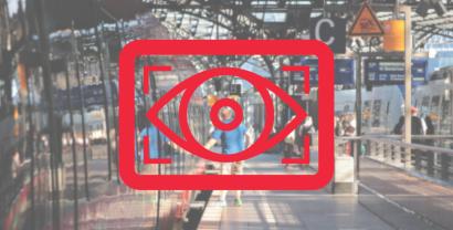 Ein Logo mit einem wachenden Auge, dahinter ein Bahnhof.