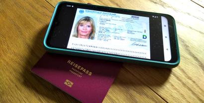 Das Bild von einem Personalausweis auf einem Smartphone, welches auf einem Reisepass liegt.