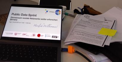 Foto vom Display eines Laptops mit einer Begrüßungsfolie mit der Überschrift "Public Data Sprint, Gemeinsam soziale Netzwerke weiter erforschen"