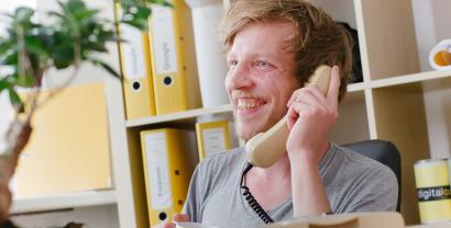 Ein Digitalcourage-Mitarbeiter an einem Schnurtelefon, lachend.