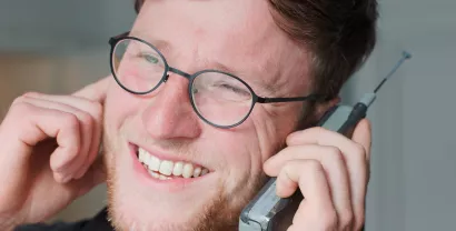 Ein Digitalcourage-Mitarbeiter mit einem alten Mobiltelefon mit Antenne.