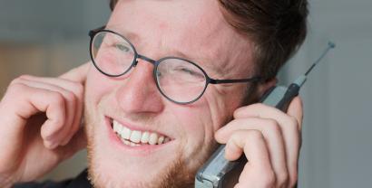 Ein Digitalcourage-Mitarbeiter mit einem alten Mobiltelefon mit Antenne.