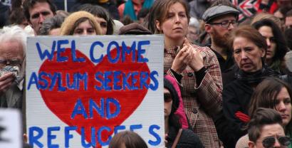 Demonstrant.innen mit einem großen Schild: "Welcome asylum seekers and refugees".