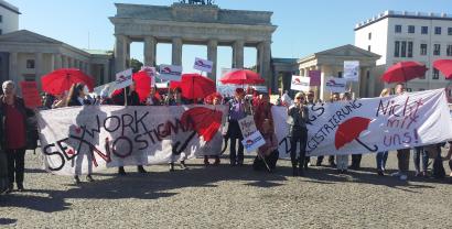 Demonstrant.innen mit Bannern vor dem Brandenburger Tor.