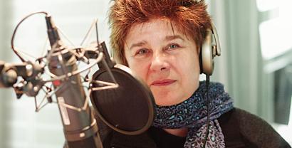 Portraitaufnahme von Rena Tangens mit Kopfhörern hinter einem Mikrofon (in einem Tonstudio).
