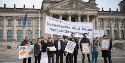 Protestteilnehmer.innen vor dem Reichstagsgebäude. Sie halten ein Transparent mit folgendem Text: „Grundrechte sind keine Verhandlungsmasse.“