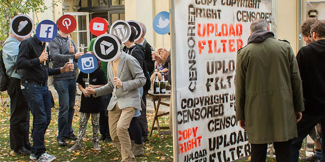 Menschen, die sich ein Schild mit den Logos bekannter Sozialer Medien vor das Gesicht halten.