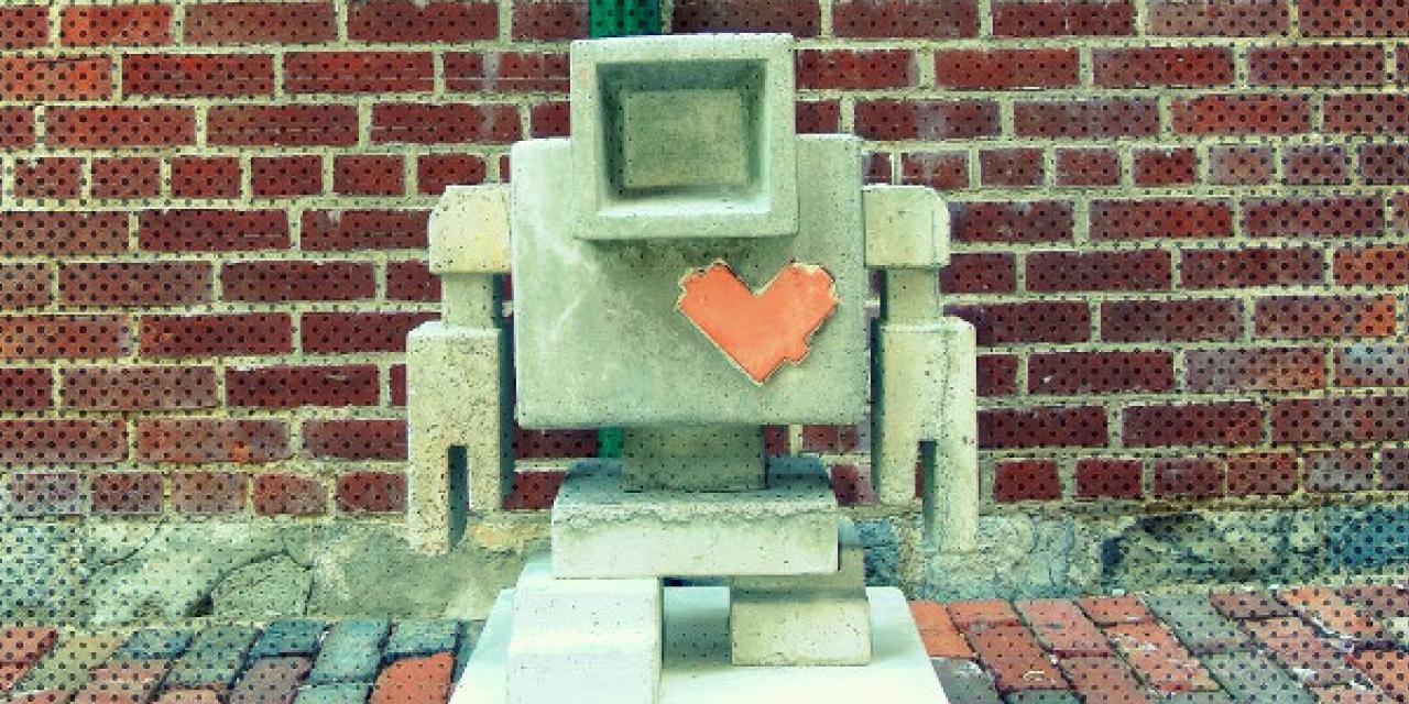 Roboter mit Herz vor einer Backsteinmauer. 