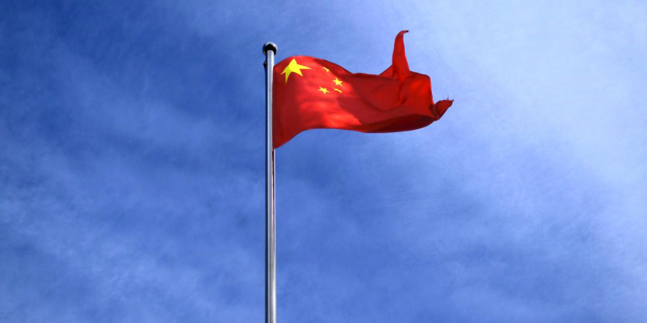 Die Flagge Chinas vor einem blauen Himmel (Froschperspektive).